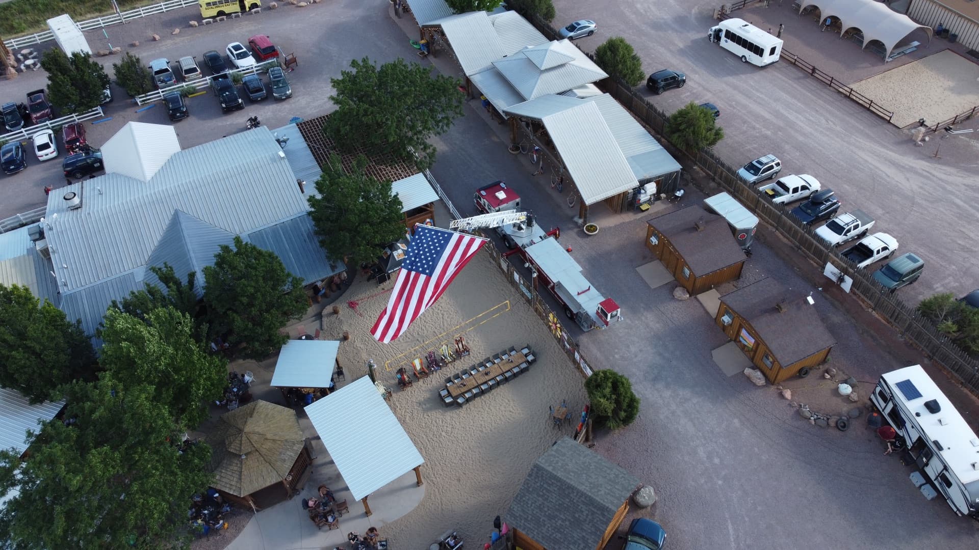 Sweeping wide-angle aerial of the entire Whitewater Bar & Grill compound — timber pavilion, volleyball court, parking, and the surrounding Fremont County canyon landscape.