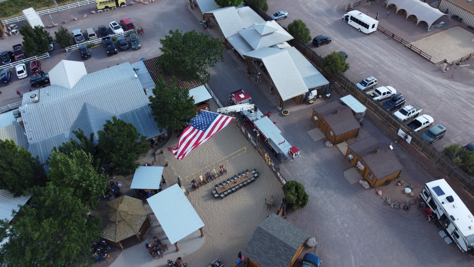 Aerial view from the northeast showing the property layout, volleyball court, pavilion roofline, and canyon hillsides.