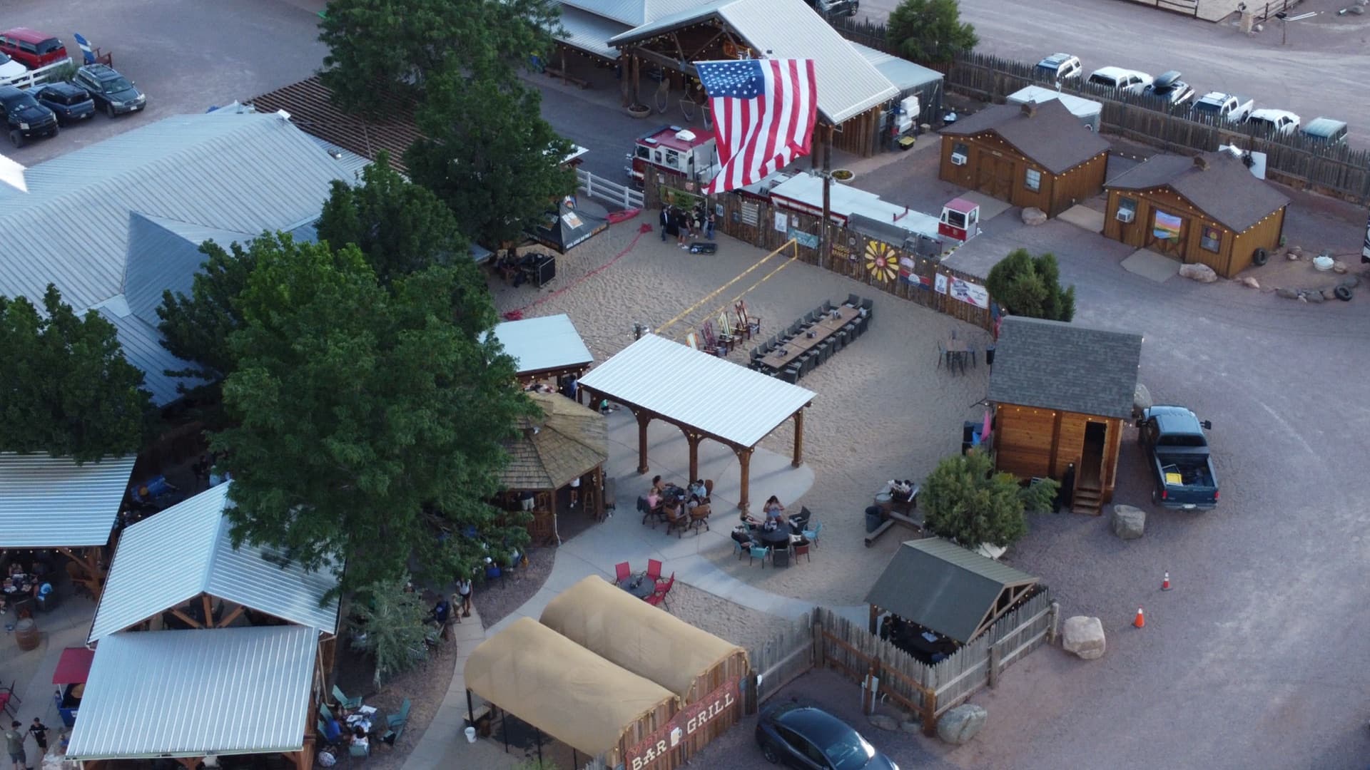Angled aerial of the dining pavilion, stage area, and bar structure with guests enjoying the July 4th celebration.