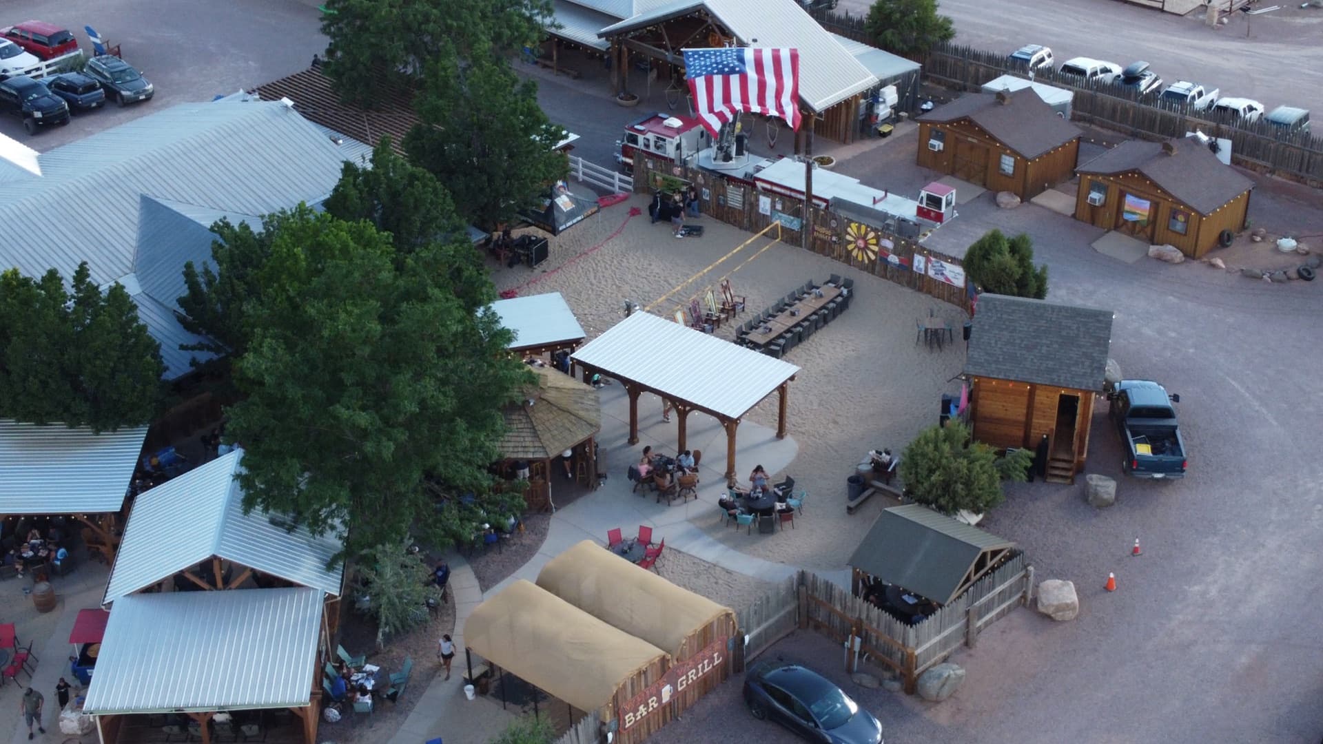 Golden hour aerial capturing the warm light across the wooden structures and string lights.